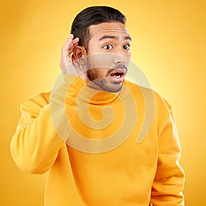 Asian man, listening and gossip with hand on ear in studio background for information. Shock, hearing and male person