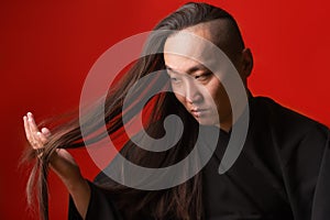 Asian man with long thick hair on a red background