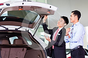 Asian man looking at car in dealership