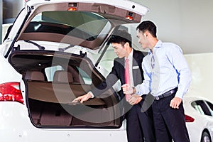 Asian man looking at car in dealership