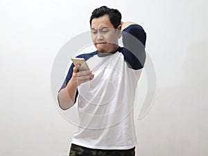 Asian man looking at his phone with upset displeased expression, male person just receiving bad news