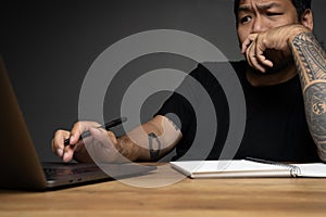 Asian man looking at monitor with focusing face on wooden table with laptop. Concept about work remotely. Focus on face