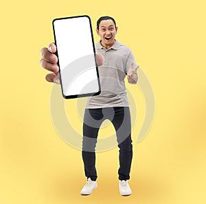 Asian man looking to camera, smiling and showing empty blank white copy space phone mock up template