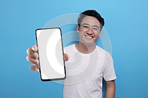 Asian man looking to camera, smiling and showing empty blank white copy space phone mock up template