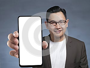 Asian man looking to camera, smiling and showing empty blank white copy space phone mock up template