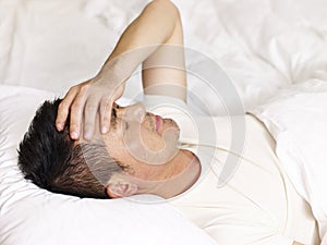 Asian man lying on back in bed