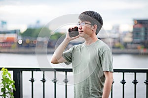 Asian man making a phone call who standing on Riverside