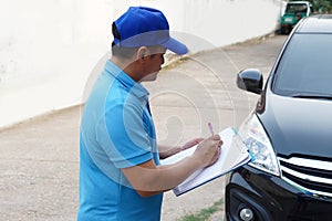 Asian man mechanic checking and evaluating broken car condition.