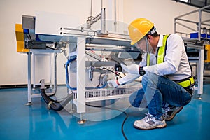 Asian man Mechanic technician worker working install and checking the electric control cabinet of conveyer in industrial factory