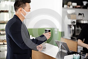 Asian man in medical with coffee going in store