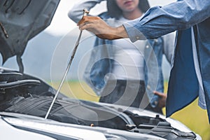 Asian man open car hood for repair as maintenance service with woman background between long road trip. Car broken and breakdown