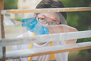 Asian man paiting wooden shelf outdoors