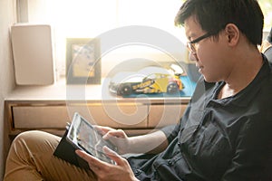 Asian man palying game on tablet at home