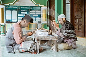 asian man paying zakat at the mosque and praying thanking god