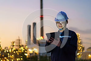 Asian man petrochemical engineer working at night with digital tablet Inside oil and gas refinery plant industry factory at night