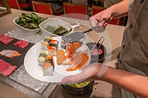 Asian man picking assortment of fresh sushi in buffet meal