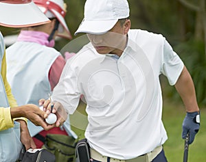 Asian man picking ball from his caddie when playing golf in course