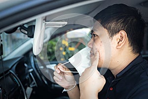 Asian man with pimple on skin,look at inflamed acne spot in front of a mirror,male pointing at acne on cheeks under face mask,skin