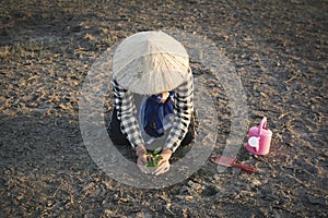 Asian man planting little green plant on cracked dry ground photo
