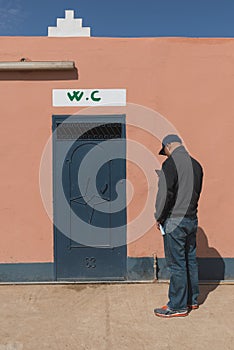 The asian man play mobile phone during waiting for toilet