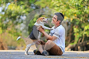 Asian man is playing with his beagle dog while having morning exercise in park