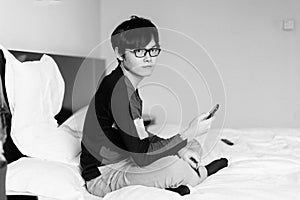 Asian man playing phone on bed