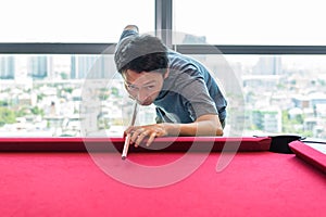 Asian man is playing snooker or billiard on red snooker table