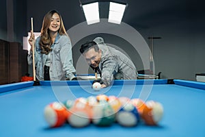 asian man poking the white ball for starting the billiard