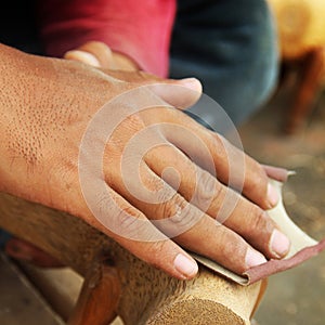 Asian man polishing sandpaper wood sculpture