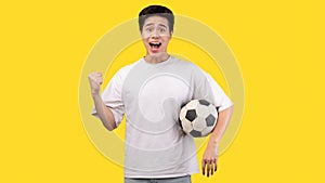 Asian man posing with soccer ball on yellow background