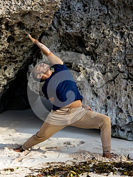 Asian man practicing variation of Virabhadrasana I. Warrior I Pose with twist. Yoga retreat. Healthcare concept. Balance and