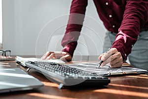 Asian man programmer holding pen to writing code data on document in clipboard while working to recheck code photo