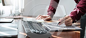 Asian man programmer holding pen to writing code data on document in clipboard while working to recheck code photo