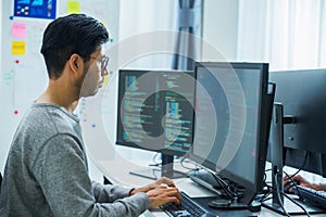 Asian man prompt engineer develop coding app with software data sitting in front of computer monitor at office