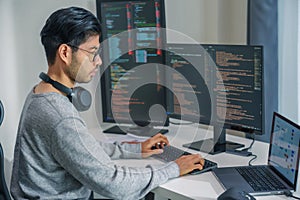 Asian man prompt engineer develop coding app with software data sitting in front of computer monitor at office