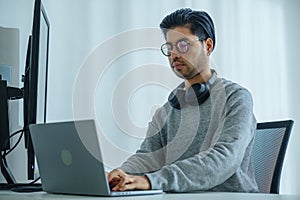 Asian man prompt engineer develop coding app with software data sitting in front of computer monitor at office