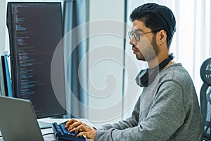 Asian man prompt engineer develop coding app with software data sitting in front of computer monitor at office
