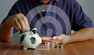 Asian man putting coin in to piggy back with coin stacking and trend graph. man is sloving financial problems with saving options photo