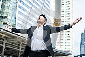 Asian man raise hand with happiness in city feels glad to get new job. Young businessman feeling happy and free after he knew the