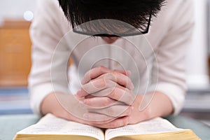 A man is reading the Holy Bible and praying in a worship room in a Christian church