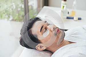 Asian man relaxation in spa salon with eye mask for under eye anti wrinkle