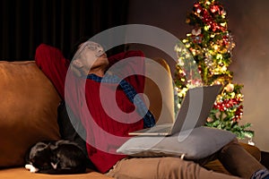 An Asian man resting on a couch with his cat, taking nap, spending Christmas night at home