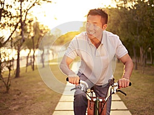 Asian man riding bike outdoors at sunset