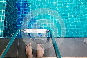 Asian man`s feet at the edge of the pool. He is going to swim