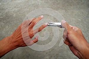 Asian man's fingernails are long and dirty. Man cutting with dirty nail scissors