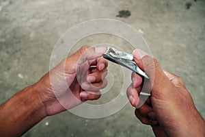 Asian man's fingernails are long and dirty. Man cutting with dirty nail scissors