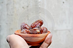 Asian man`s hand gives a date palm Phoenix dactylifera on a wooden bowl