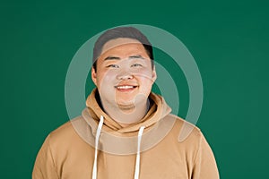 Asian man's portrait isolated over green studio background with copyspace