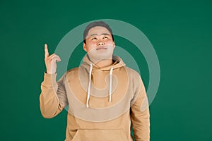 Asian man's portrait isolated over green studio background with copyspace