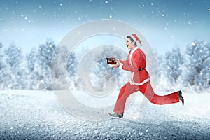 Asian man in Santa costume running while holding the gift box